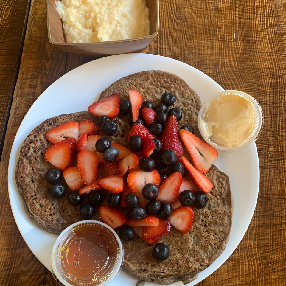 Meme's Healthy Nibbles pancakes with strawberries, blueberries, and sides of syrup and butter.