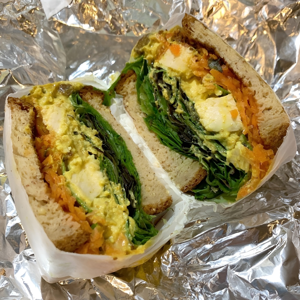 A healthy egg salad sandwich, cut in half, with lettuce and shredded carrots on whole wheat bread.