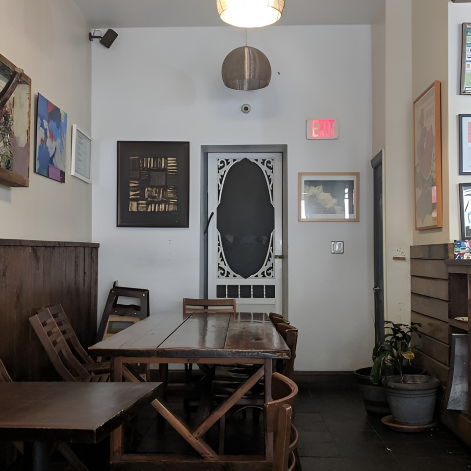 Interior of Meme's Healthy Nibbles, showing wooden tables and chairs, artwork, and a decorative door.