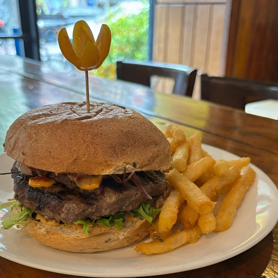 A Meme's Healthy Nibbles burger with fries on a white plate, with a window in the background.